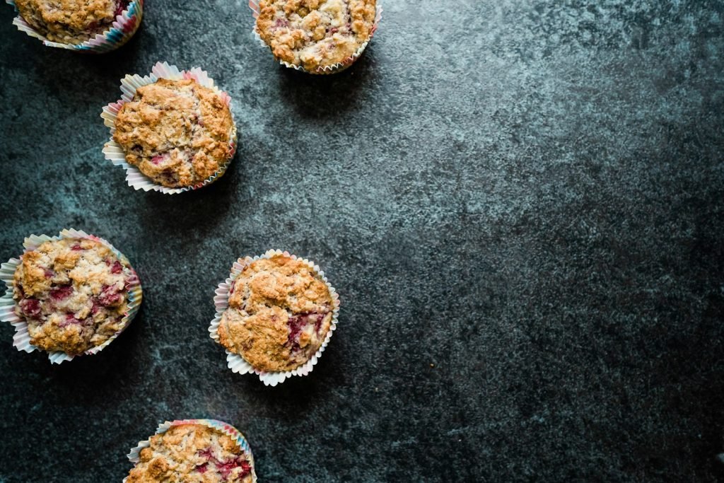 Several baked muffins with crumbs on a dark surface