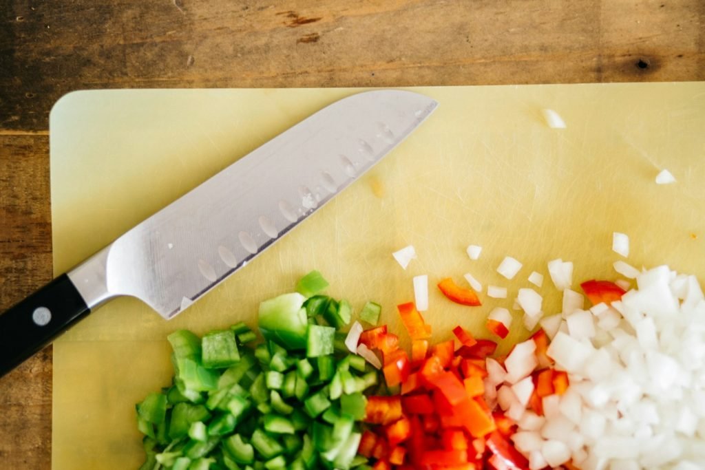 Sliced green and red peppers on a white chopping board
