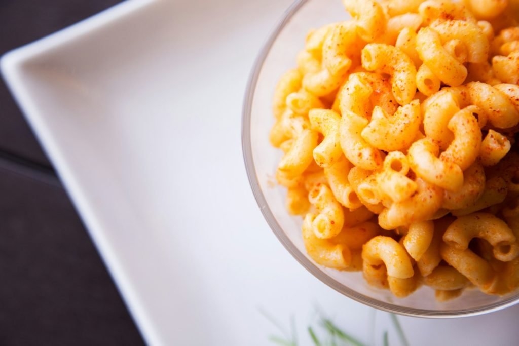 Cheesy yellow pasta in a clear glass bowl