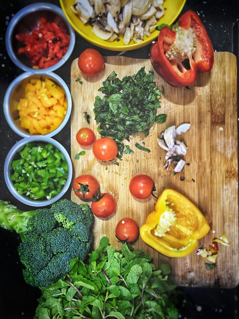 Tomatoes, sliced yellow pepper and broccoli on a wooden chopping board