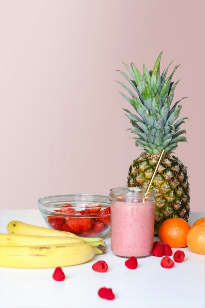 A strawberry drink next to fresh fruit on a table